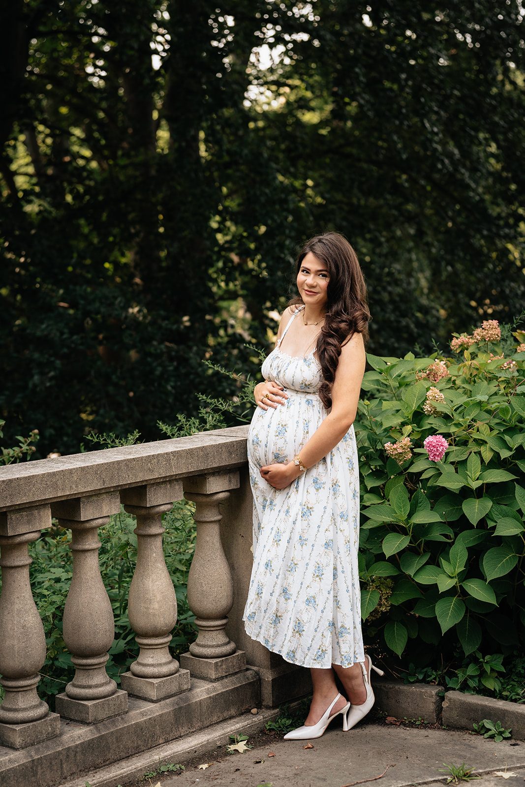 Portrait of Hala standing among pink hydrangeas and green foliage in the Italian Cultural Gardens in Cleveland