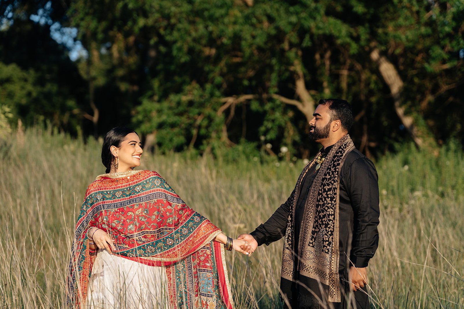 Ramneet swinging her dupatta open mid-walk through the meadow while Harry reaches for her hand