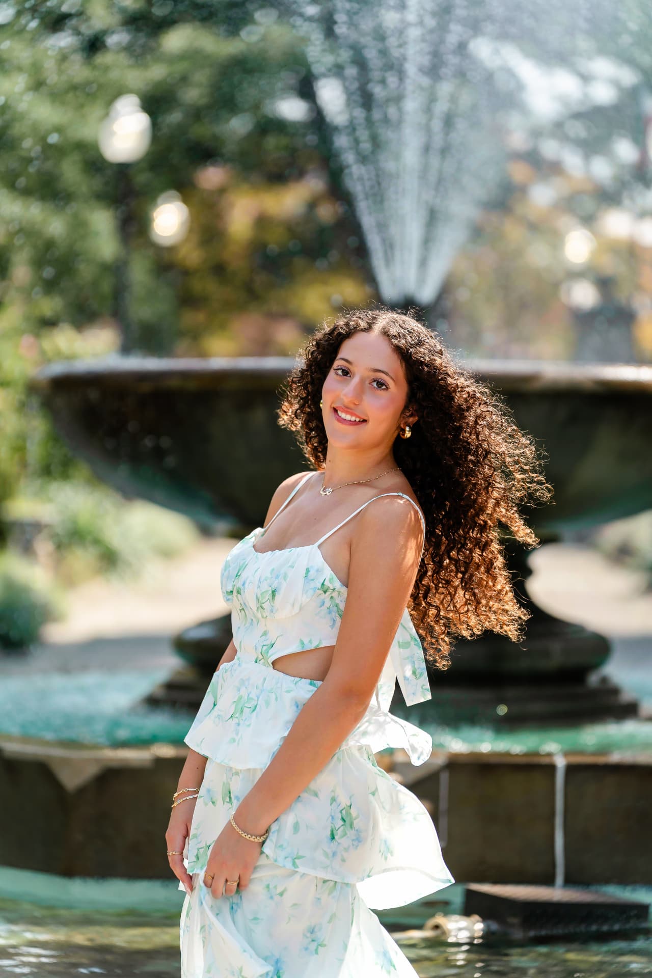 Senior portrait of Naya beside a garden fountain surrounded by greenery in Cleveland