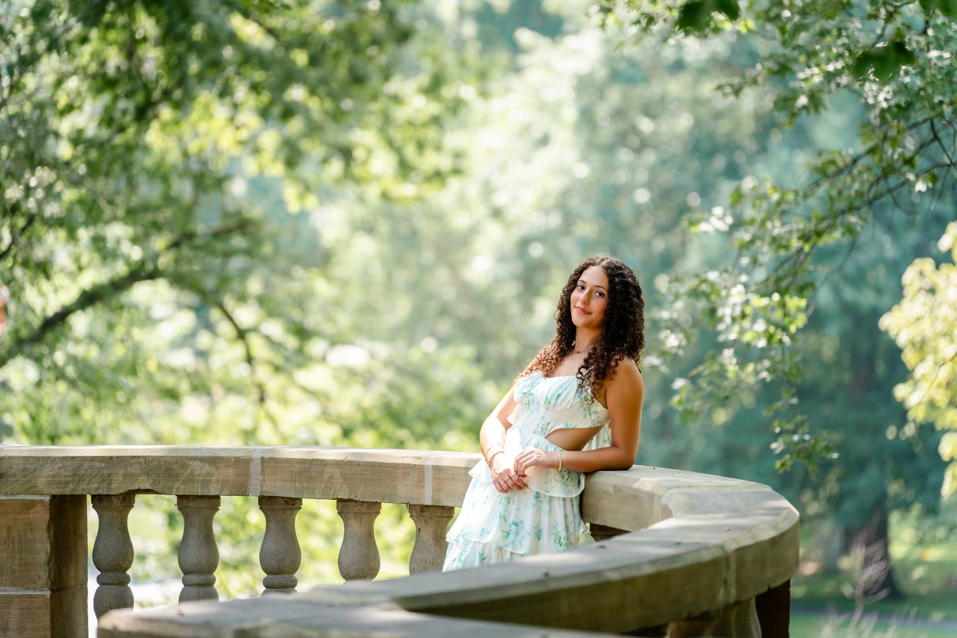 Senior portrait of Naya framed by garden foliage and stone architecture in Cleveland